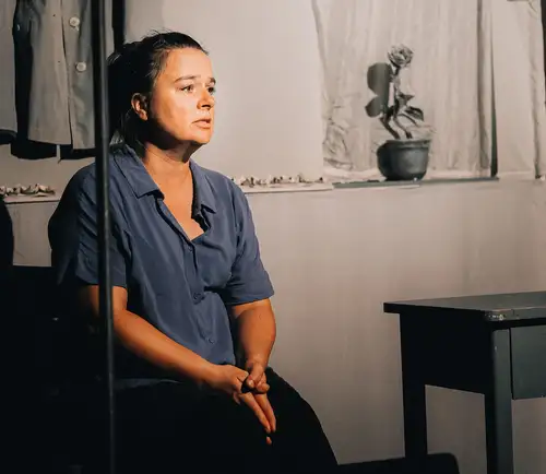 Eine Frau in grau sitzt in einem grauen Raum und schaut traurig.