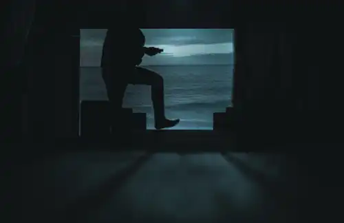Schattenhafte Konturen eines Stegs vor einer Projektion der Nordsee. Dazwischen der Schatten eines hüpfenden Menschen.